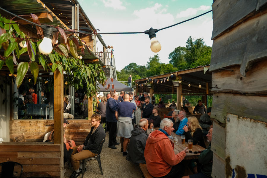 People enjoying food & drink in the courtyard underneath festoon lighting at Stroud Brewery