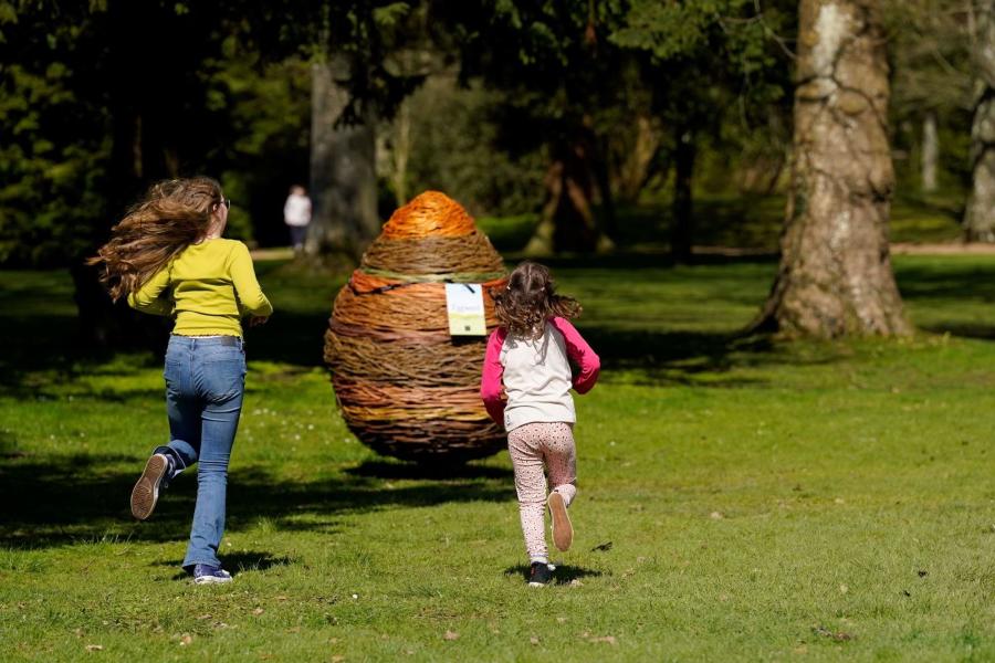 Two children run towards a giant wicker egg in the grounds of Blenheim Palace