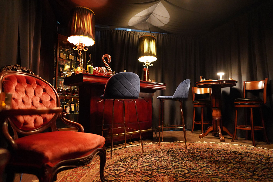 Inside of Room 901, plush velvet chair in front of a mahogany colored private bar.