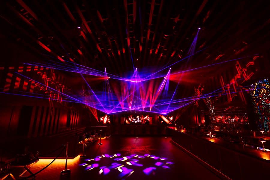 The dance floor of The Angeles with laser lighting and stained glass behind the bar