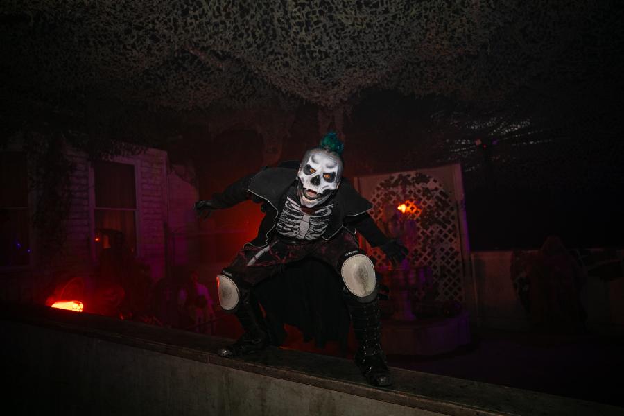 A haunted house character with a skull-like mask strikes a scary pose
