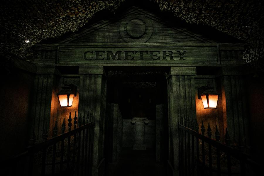 A cemetery crypt at night with two lanterns flanking the entrance