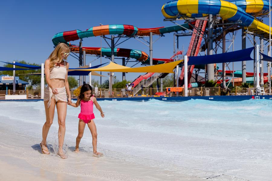 Mother and daughter walking along Hurricane Harbor with water slides in the background