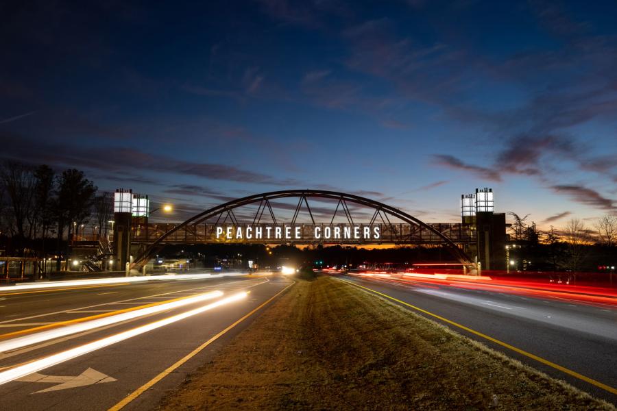 Landscape photo of bridge over 2 lanes Bridge says "Peachtree Corners" in large white letters