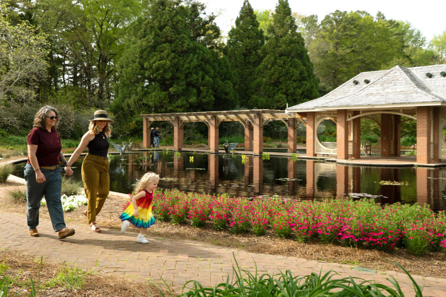 A female couple walking with their running daughter at the Huntsville Botanical Garden