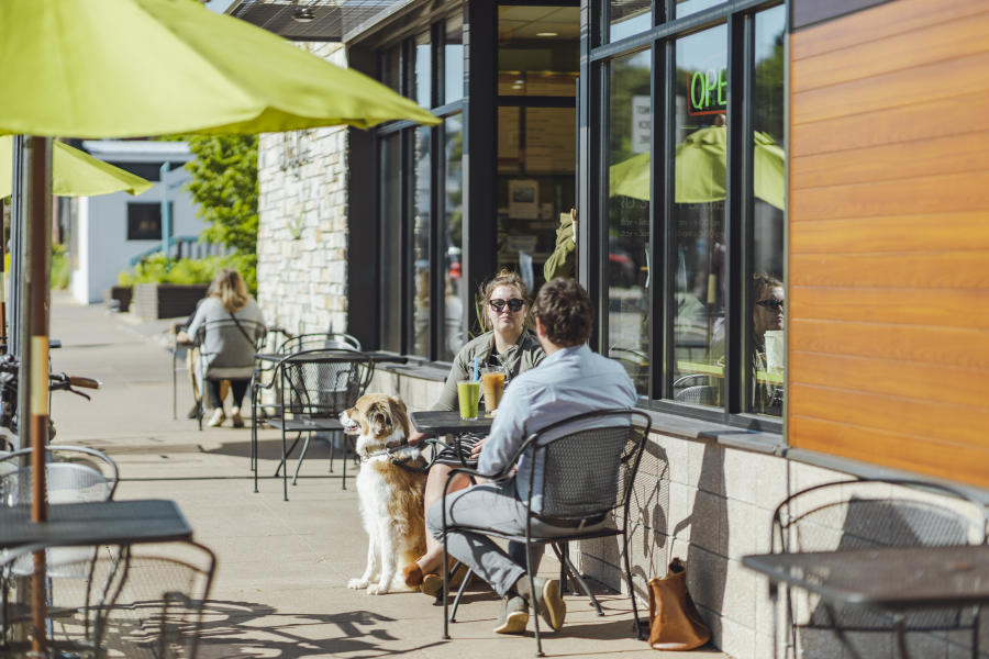 A couple dining outside with their dog at Third St. Bagel