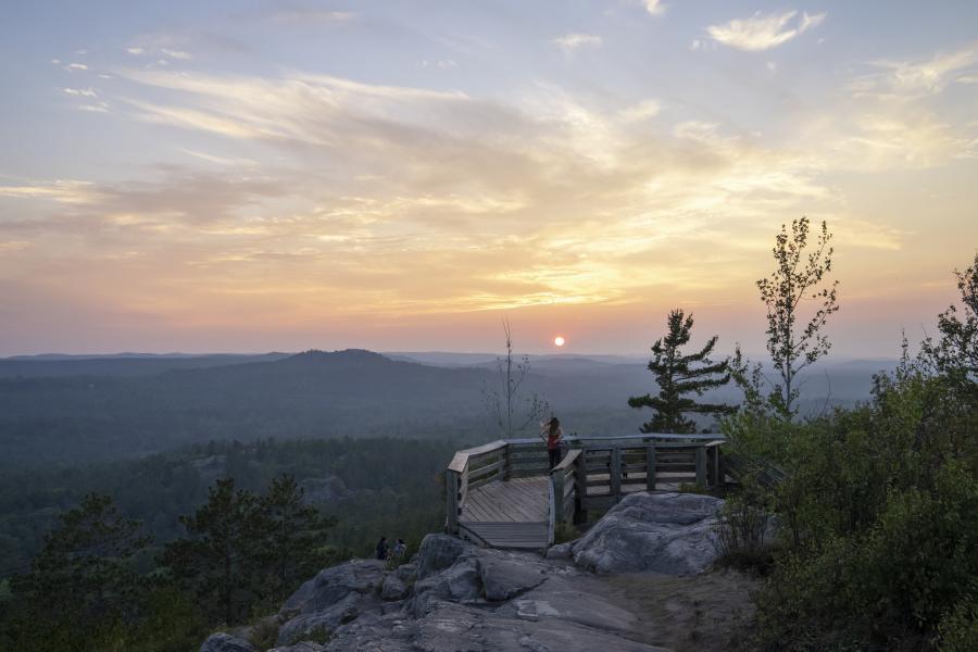 A women overlooking the greenery at sunset on the observation deck at the top of Sugarloaf Mountain in Marquette, MI