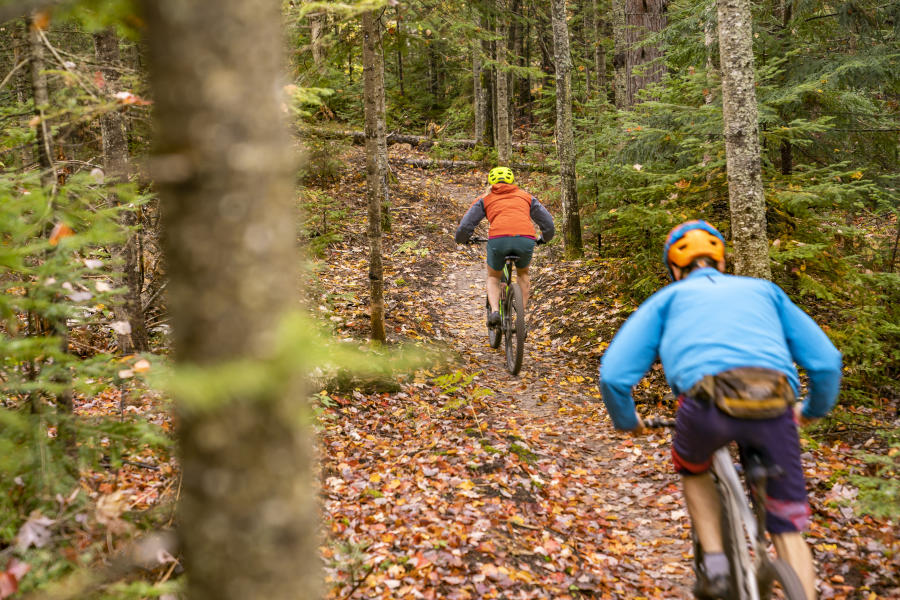 A couple mountain biking amongst the vibrant fall foliage in Big Bay, MI.