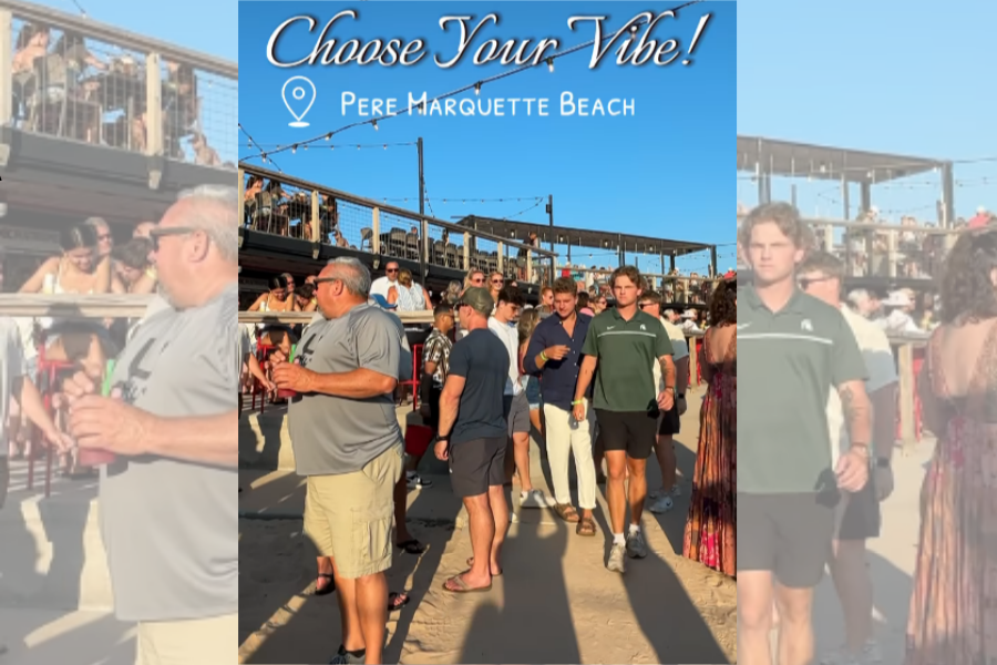 Busy day at Pere Marquette Beach with a crowd of people enjoying the sunny weather under a banner that reads 'Choose Your Vibe!'