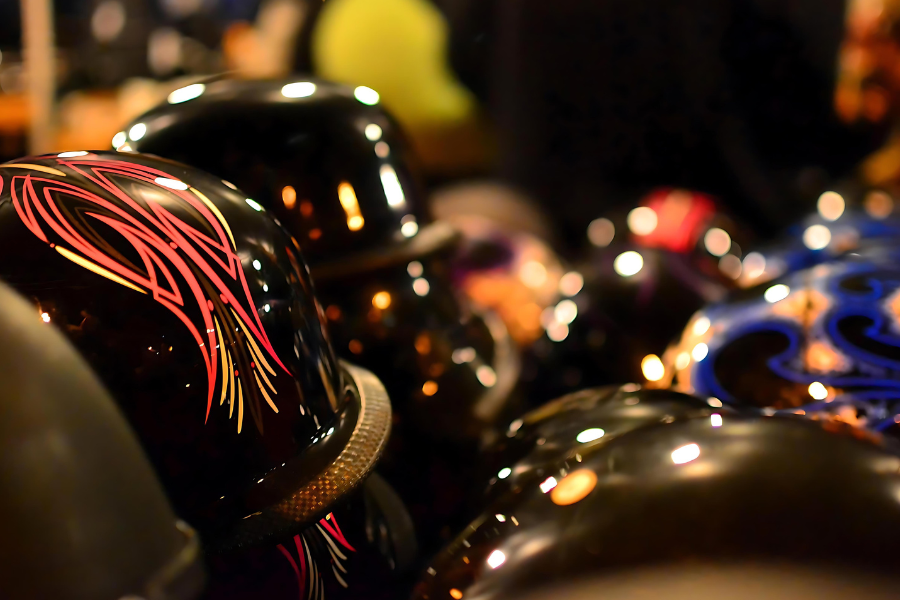 Motorcyle helmets lined up on seats of bikes reflect nightime lights at Muskegon Bike Time Rebel Road