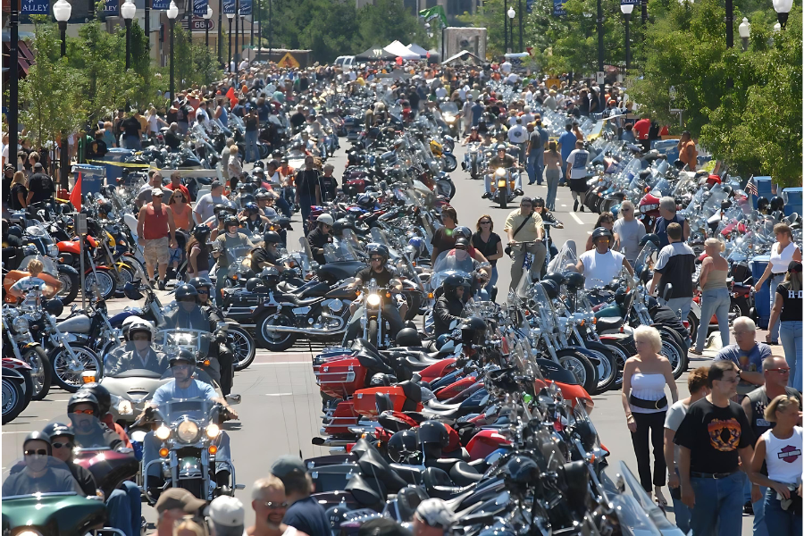 A large crowd of people and motorcycles fill a street at Muskegon Bike Time Rebel Road
