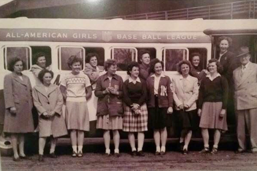 Group of players from the All-American Girls Professional Baseball League standing in front of a team bus.