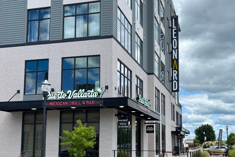 Exterior view of a modern building with "Leonard" signage at the top and "Puerto Vallarta Mexican Grill & Bar" on the ground level, under a cloudy sky.