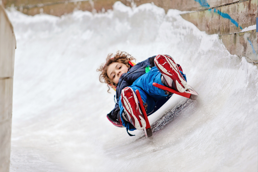 A child sledding down a snowy luge track.