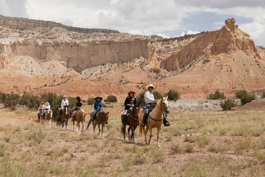 A group on a horseback riding tour under the cliffs at Ghost Ranch, Abiquiu, New Mexico