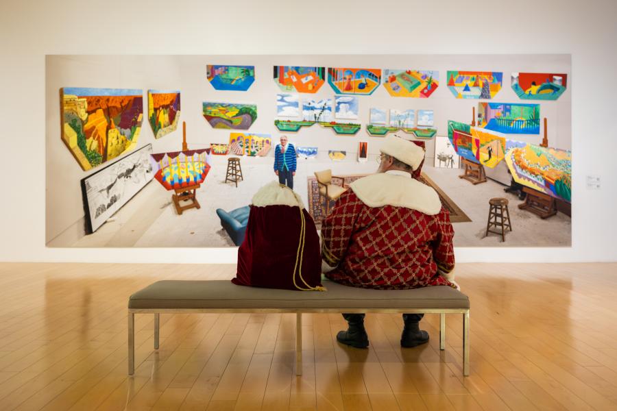 Santa is sitting on a bench looking at a painting at the Palm Springs Art Museum.