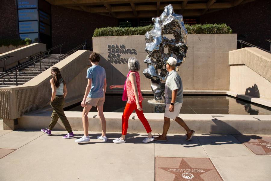 Four multi-generation family members walking in front of the Palm Springs Art Museum.
