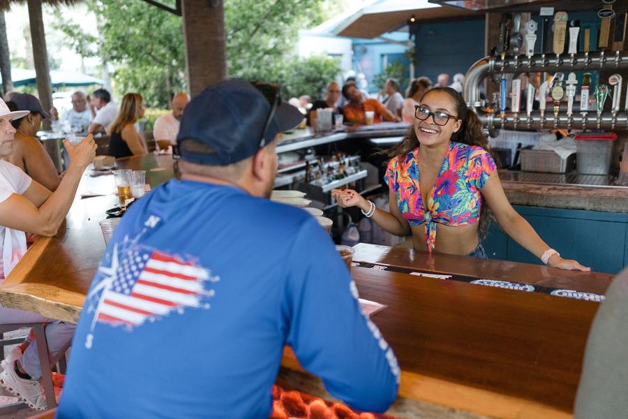 The back of a man being served at an outdoor tiki bar