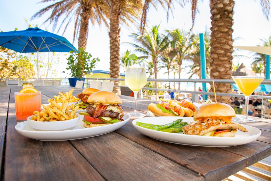 four entrees on a wooden table on a patio overlooking the ocean