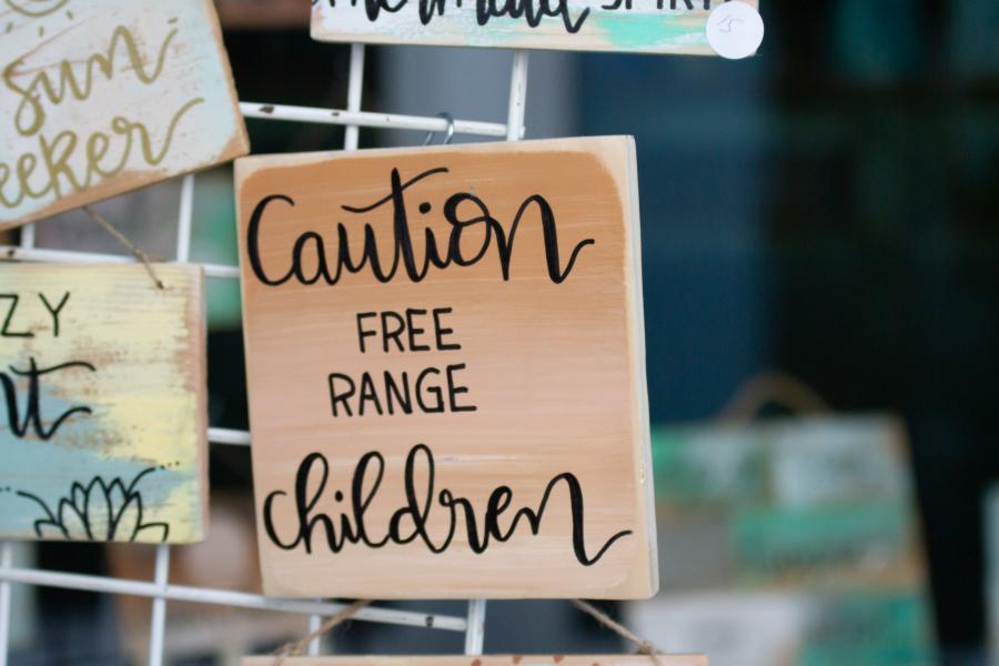A display of homemade wooden signs. The center sign says, "Caution, Free Range Children"