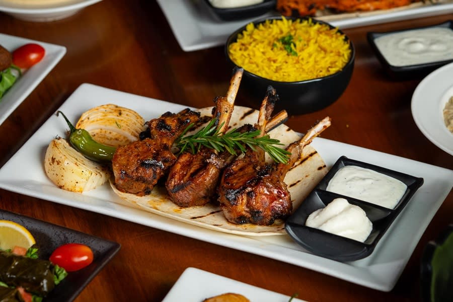 Five grilled lamb chops on unleavened bread with two ramekins of white dipping sauces