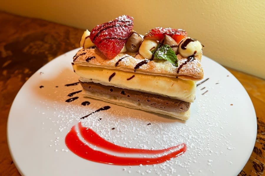 a puff pastry stuffed with Nutella and topped with strawberries, hazelnuts and powdered sugar