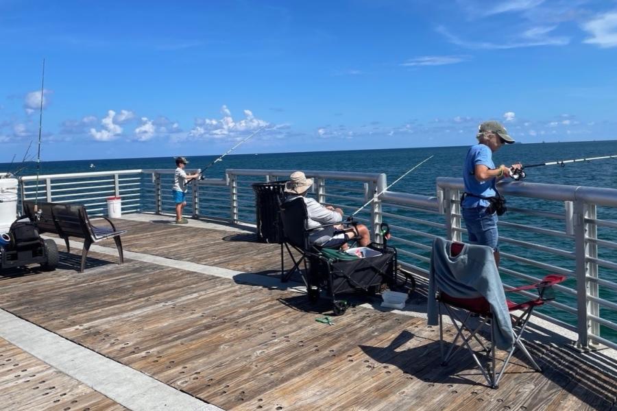 Two older men fishing with a young boy on the Pompano Beach Fishing Pier