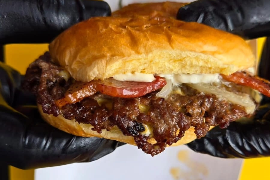 Gloved hands holding a juicy smash burger