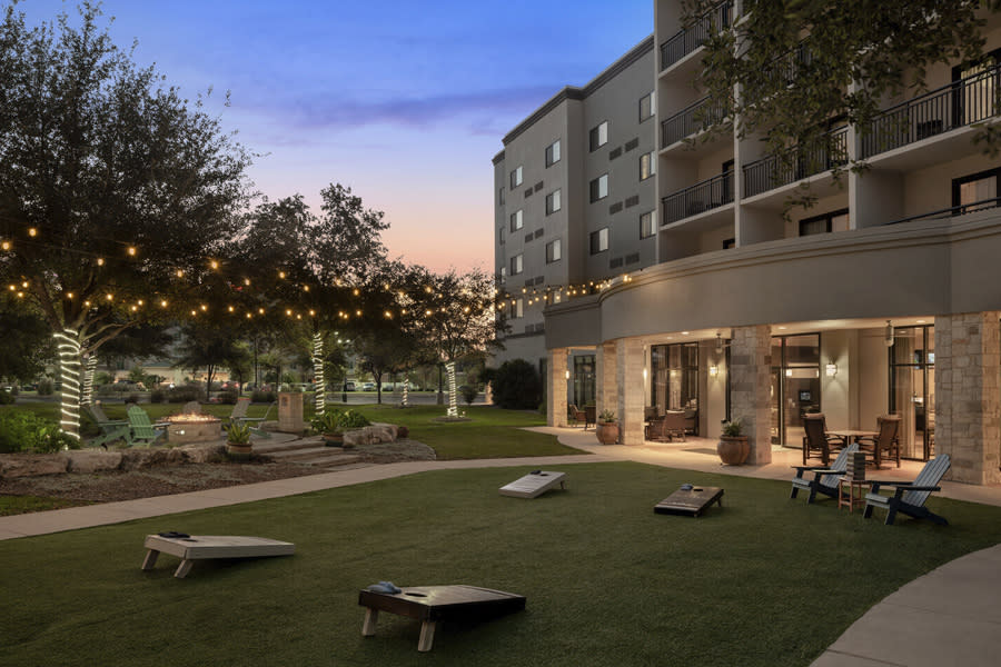 Hotel patio with cornhole and outdoor lighting