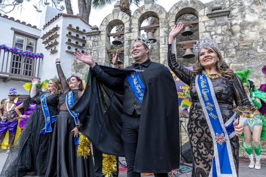 People dressed in costumed royalty waving to crowd at Arneson River Theatre.
