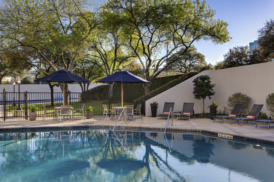 Hotel pool with lounge chairs and blue umbrellas