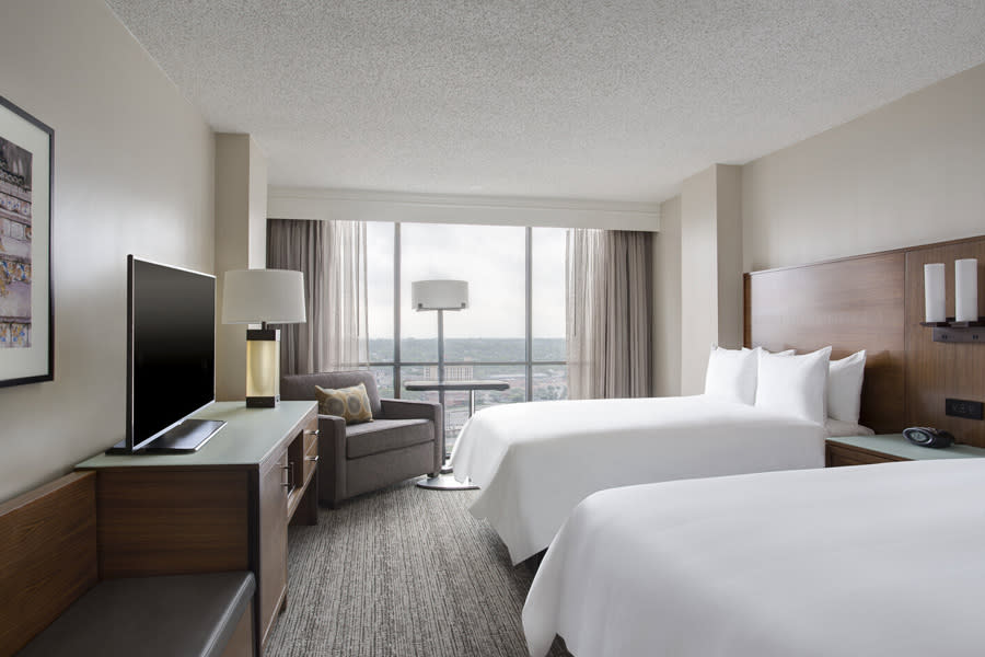 Hotel room with large window and white linens on two beds