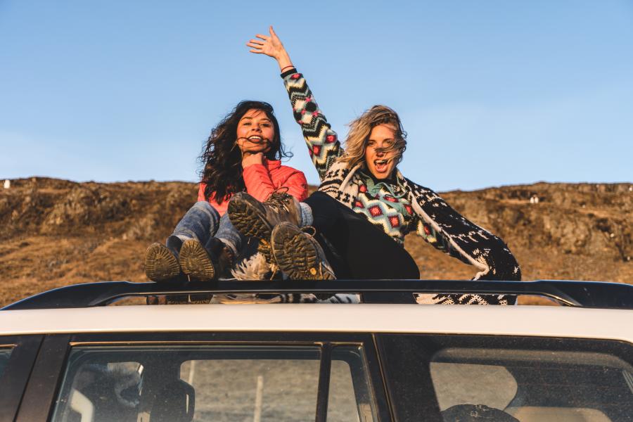 Girls-waving-on-top-of-a-car-during-road-trip