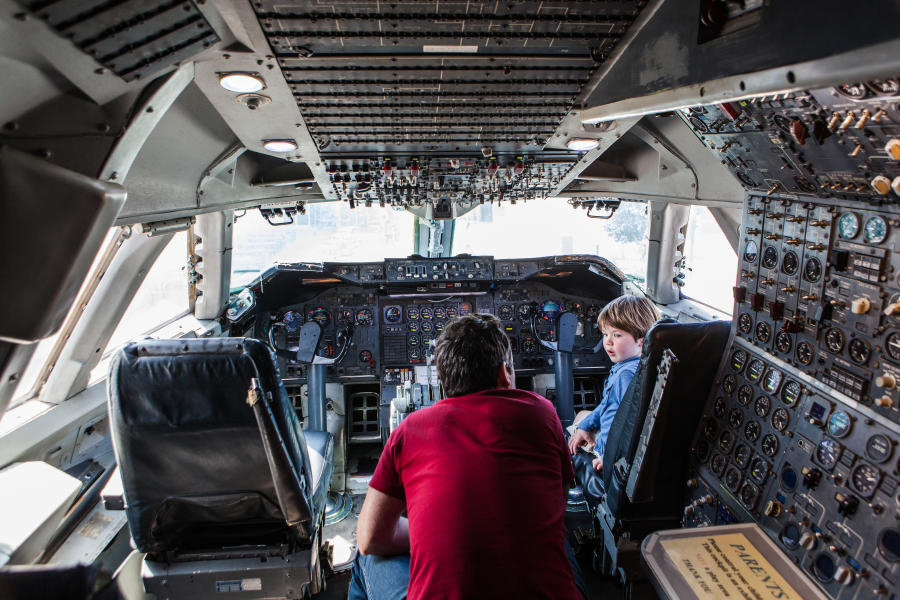 Kid experiencing the flight deck at Hiller Aviation Museum with a tour guide