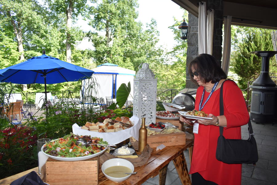 Woman at networking event at Saratoga National Golf Club grabbing food from buffet