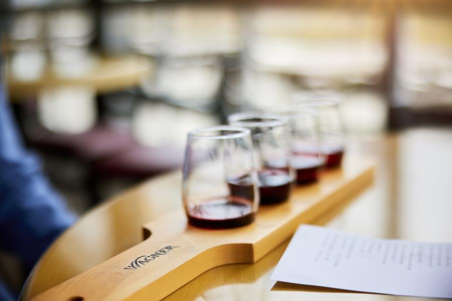 four stemless wine glasses with red wine on a wooden slab