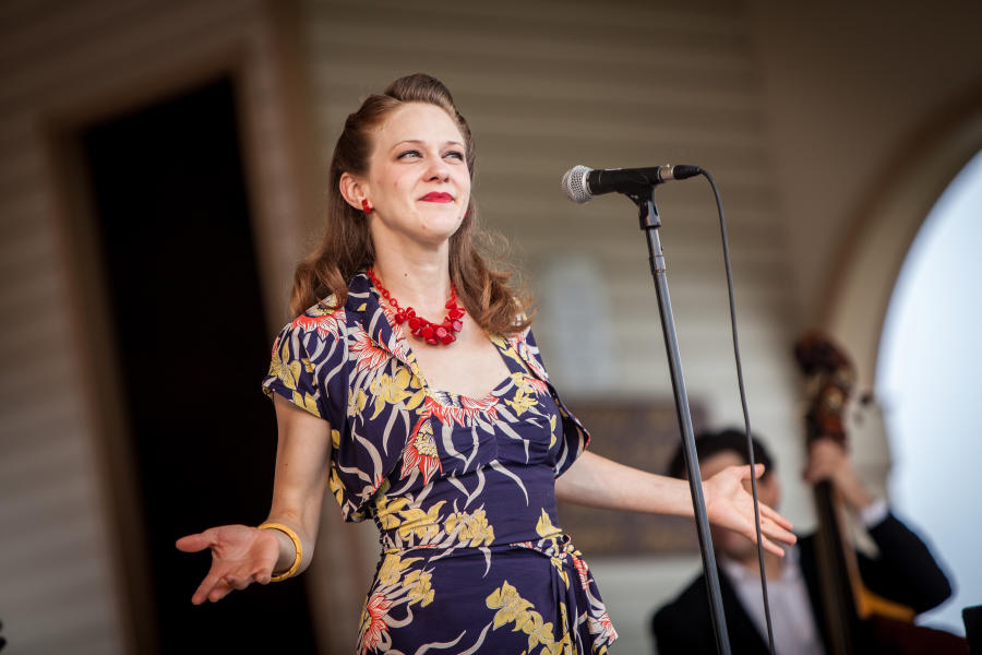 A woman stands at a microphone while performing in the New Town Concert Series in St. Charles, MO