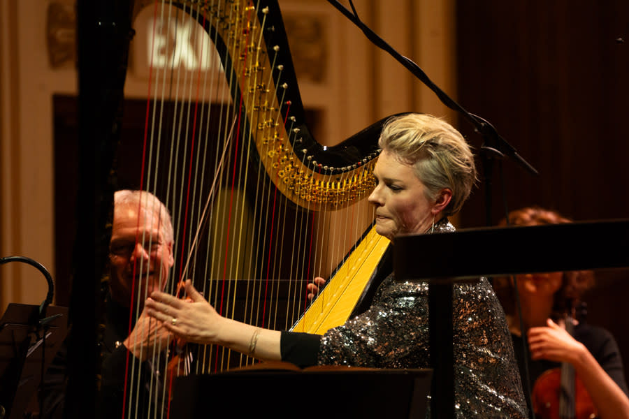 A female musician playing a harp.