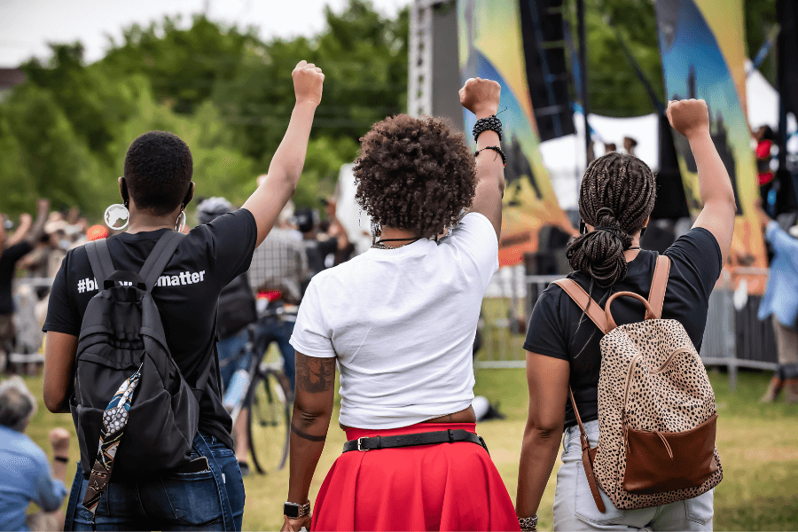 Three individuals holding their fists up at the Tulsa Juneteenth Festival