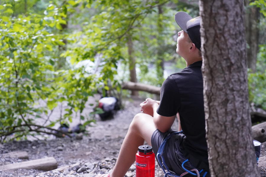 Young man sits at base of tree