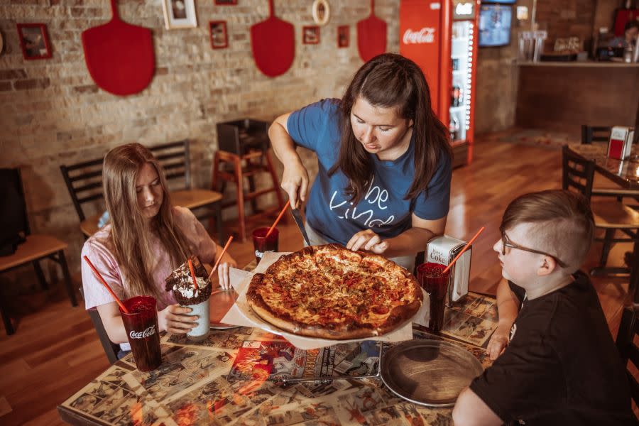 A family enjoying Provo Center Street pizza at Fat Daddy’s pizzeria with milkshakes and drinks