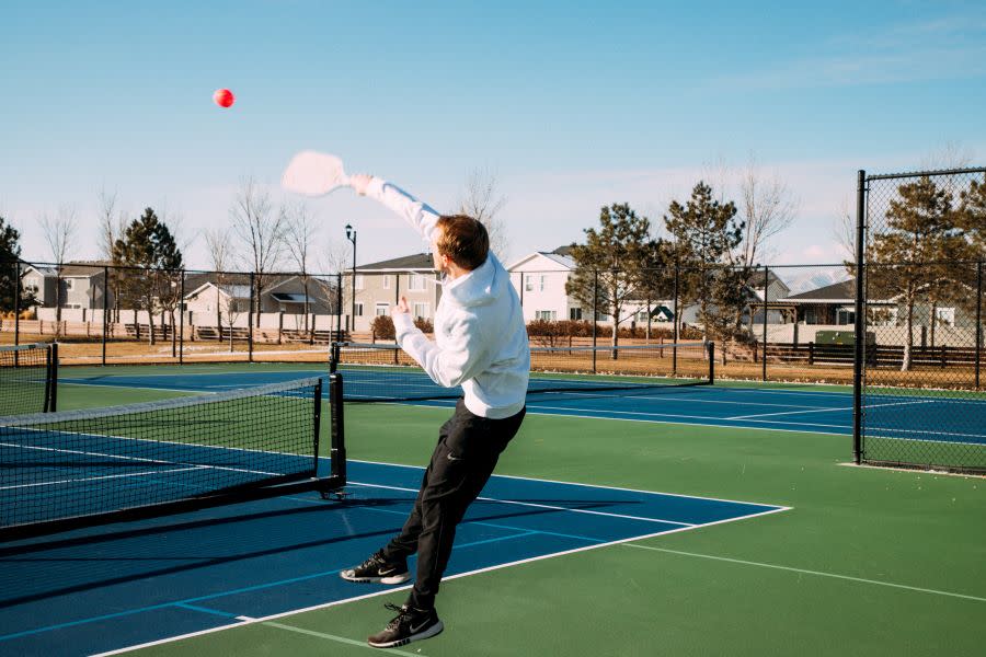 Pickleball player jumps to hit the ball with paddle
