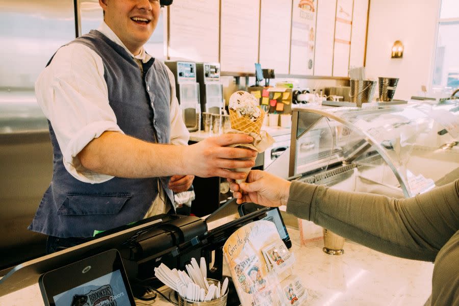 Colonial dressed ice cream shop worker hands ice cream to customer