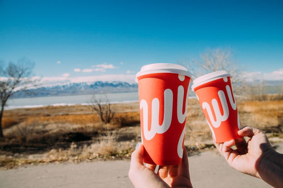 Swig coffee cups raised in cheers in front of Utah Lake