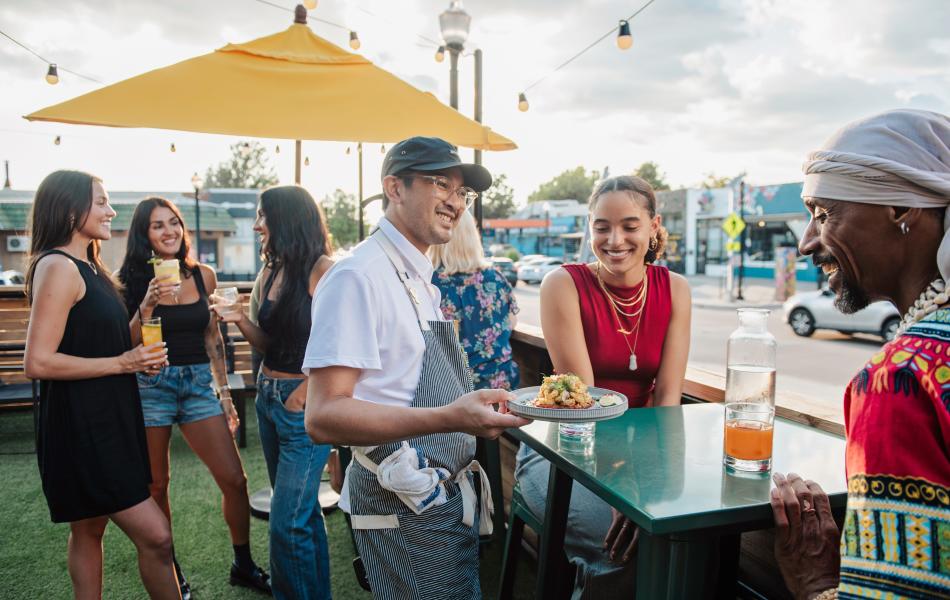 A man serving food outdoors at Bar Sen in the Plaza District