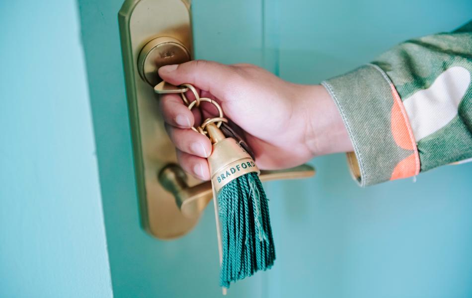 A hand inserting a blue key into a locked door
