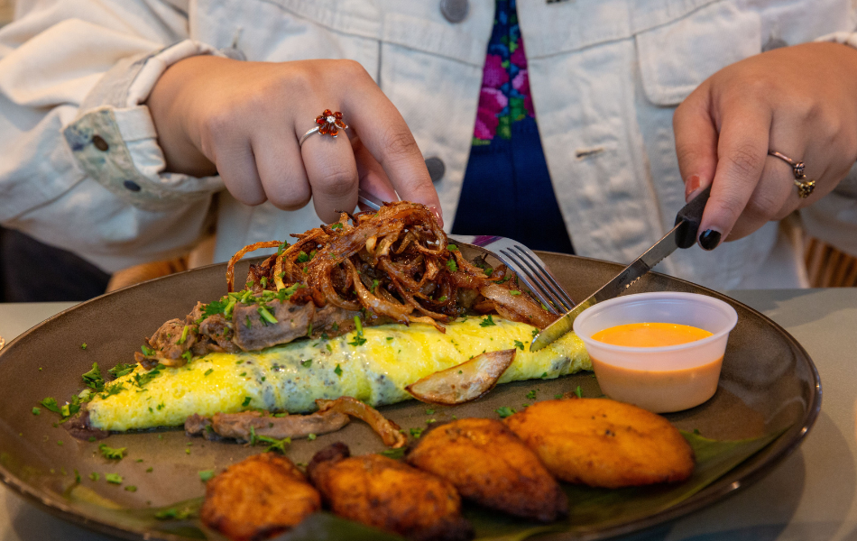 Woman cutting into omelet at Cafe Kacao