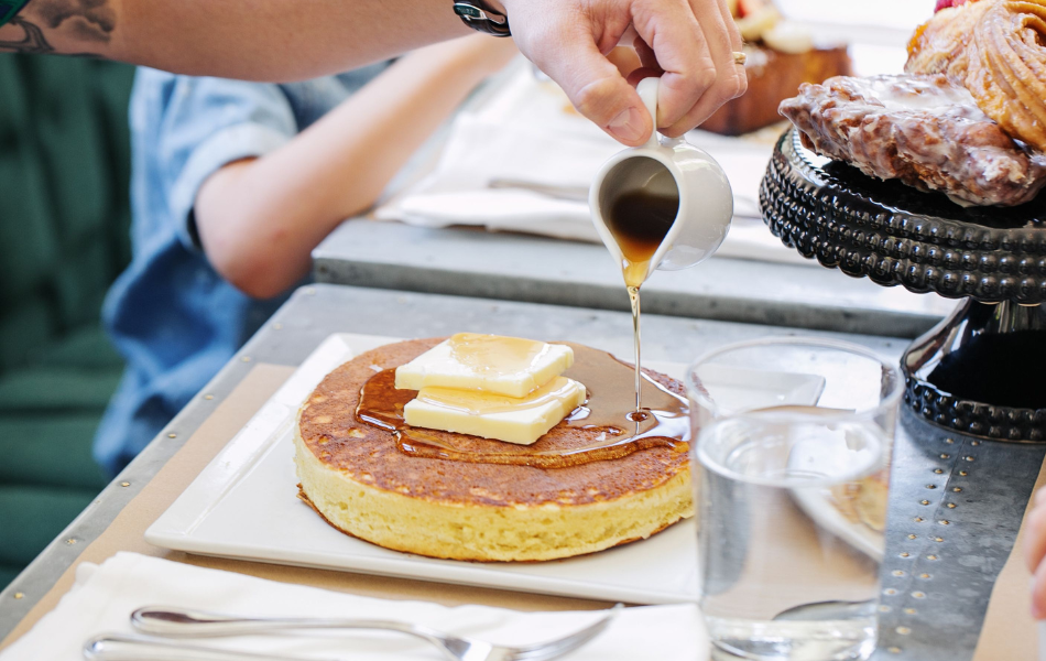 Someone pouring syrup over pancake at Kitchen No. 324