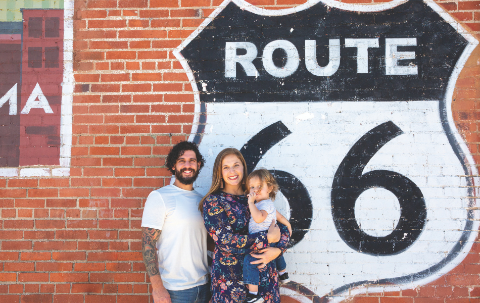 Family posing in front of Route 66 shield painted on a brick wall