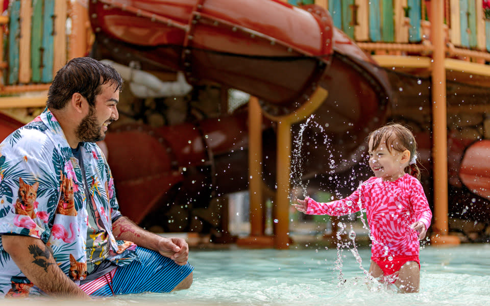 Father and small daughter splashing in water at Schlitterbahn.